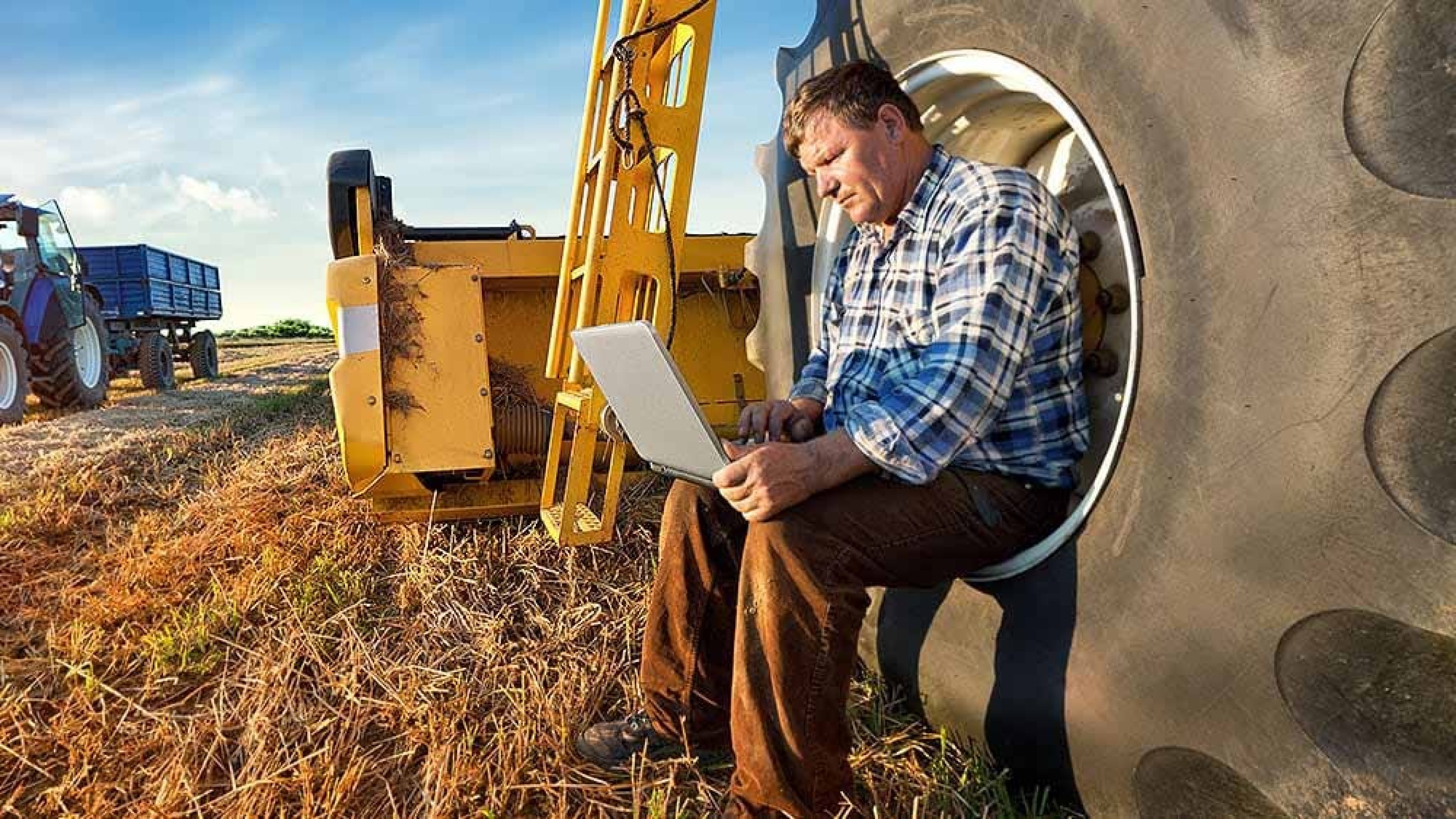 Bauer mit Laptop auf Feld