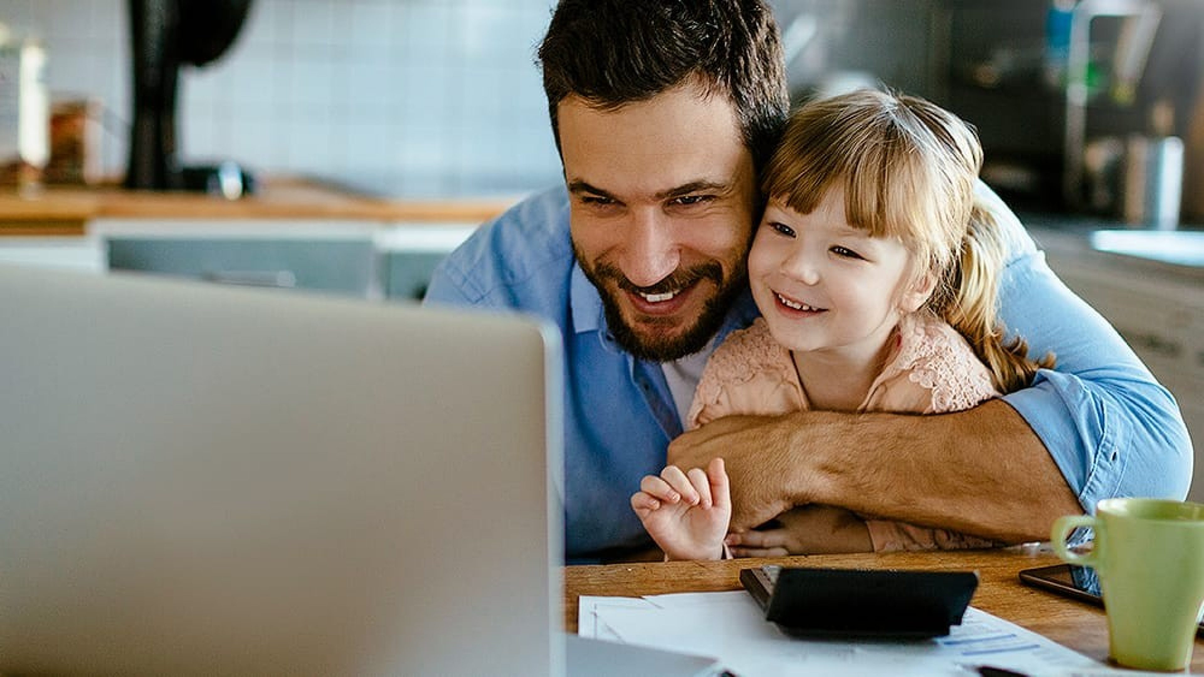 Vater und Tochter sitzen vor Laptop