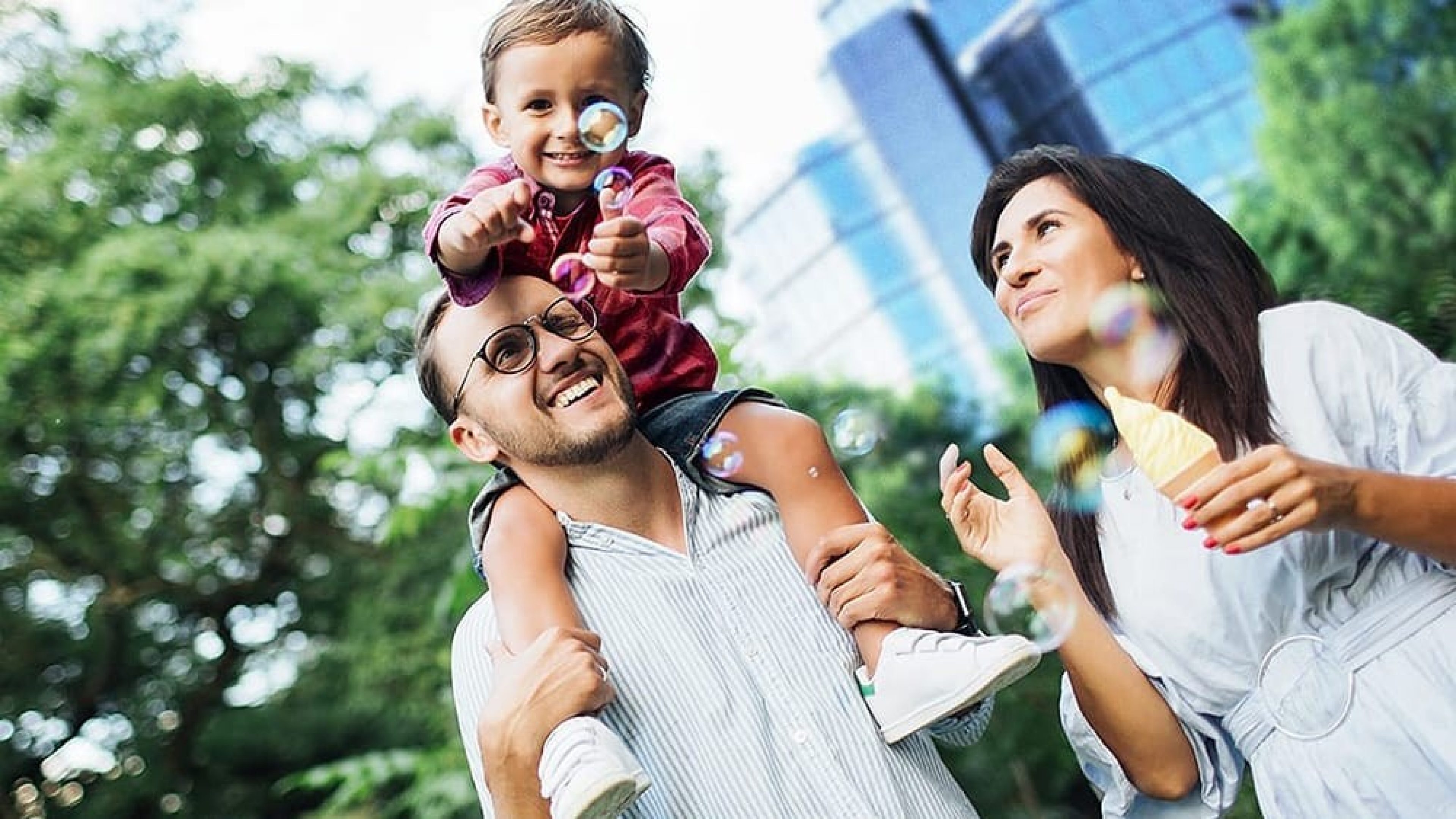 Vater trägt Sohn auf den Schultern und Mutter hält ein Eis in der Hand