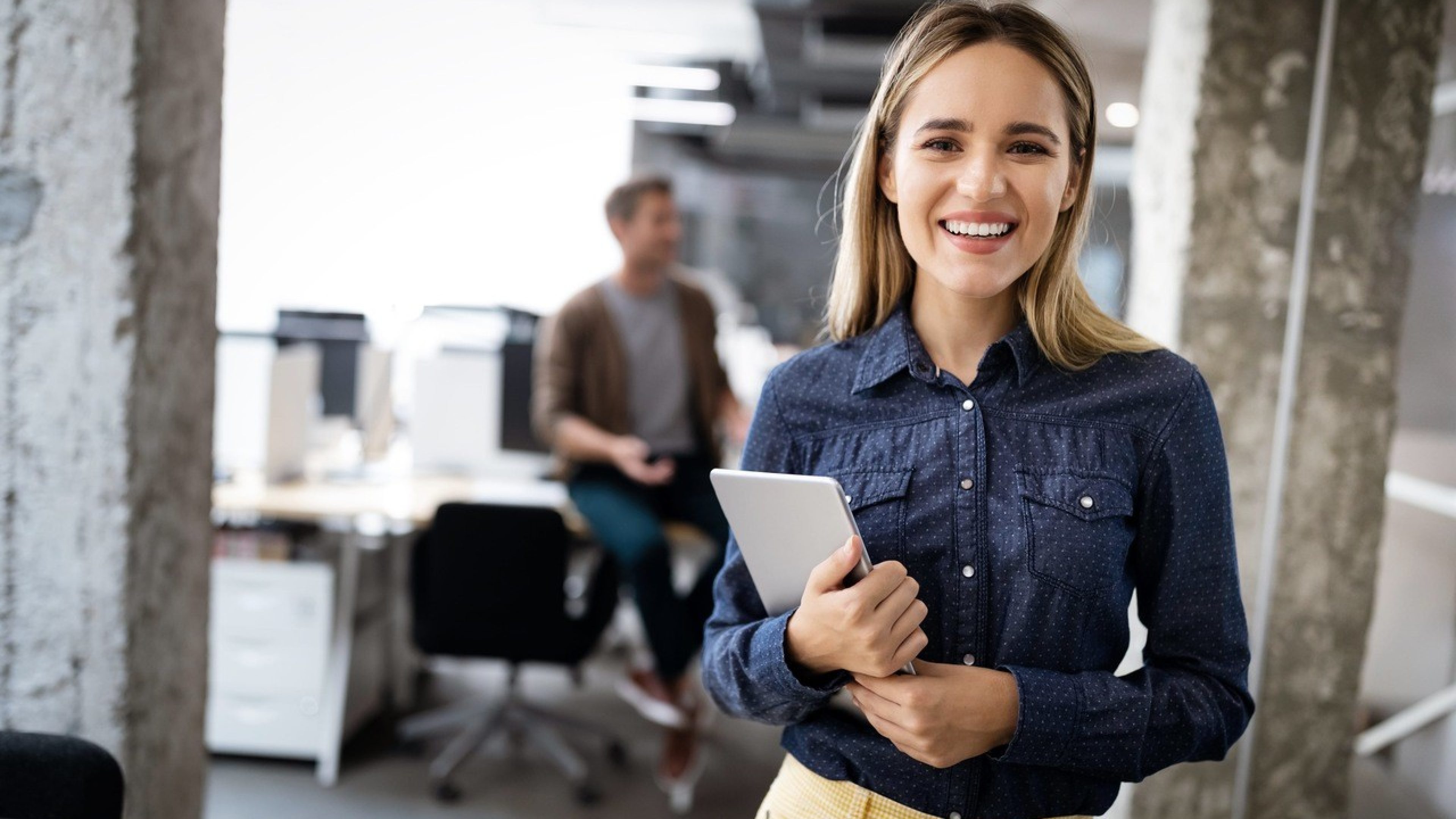 Frau im Büro hält Tablet in der Hand und lächelt