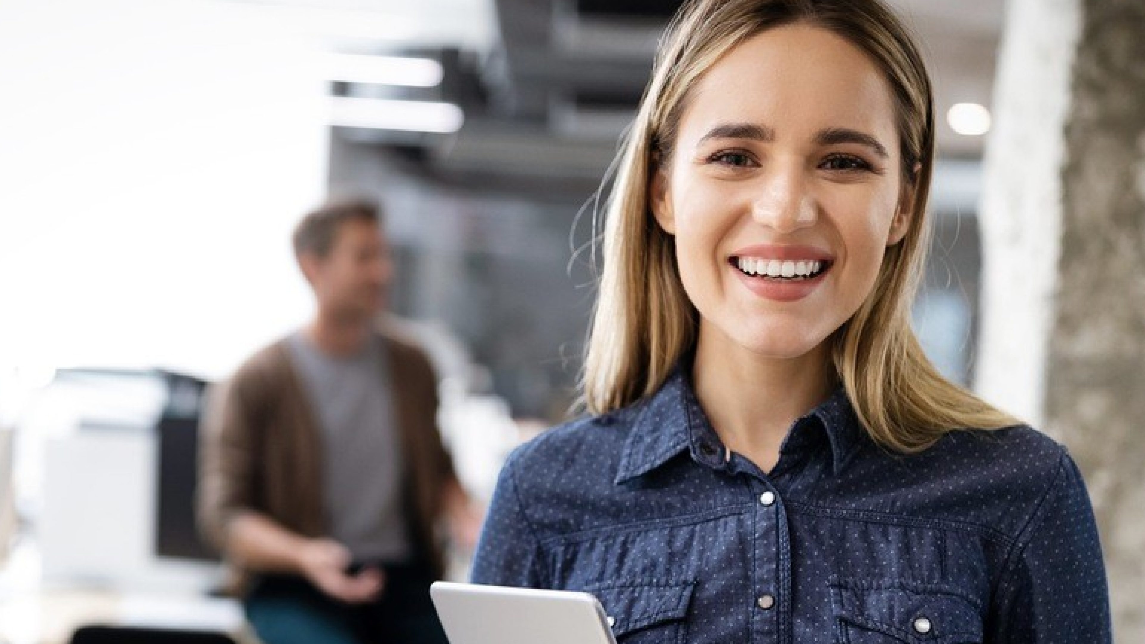 Frau im Büro hält Tablet in der Hand und lächelt