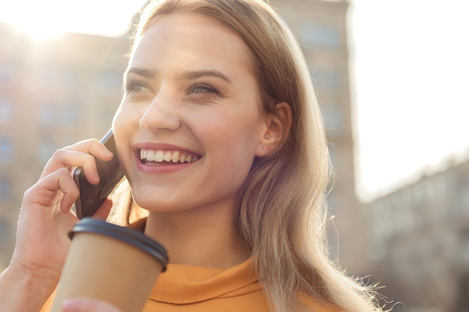 Frau mit Kaffeebecher telefoniert