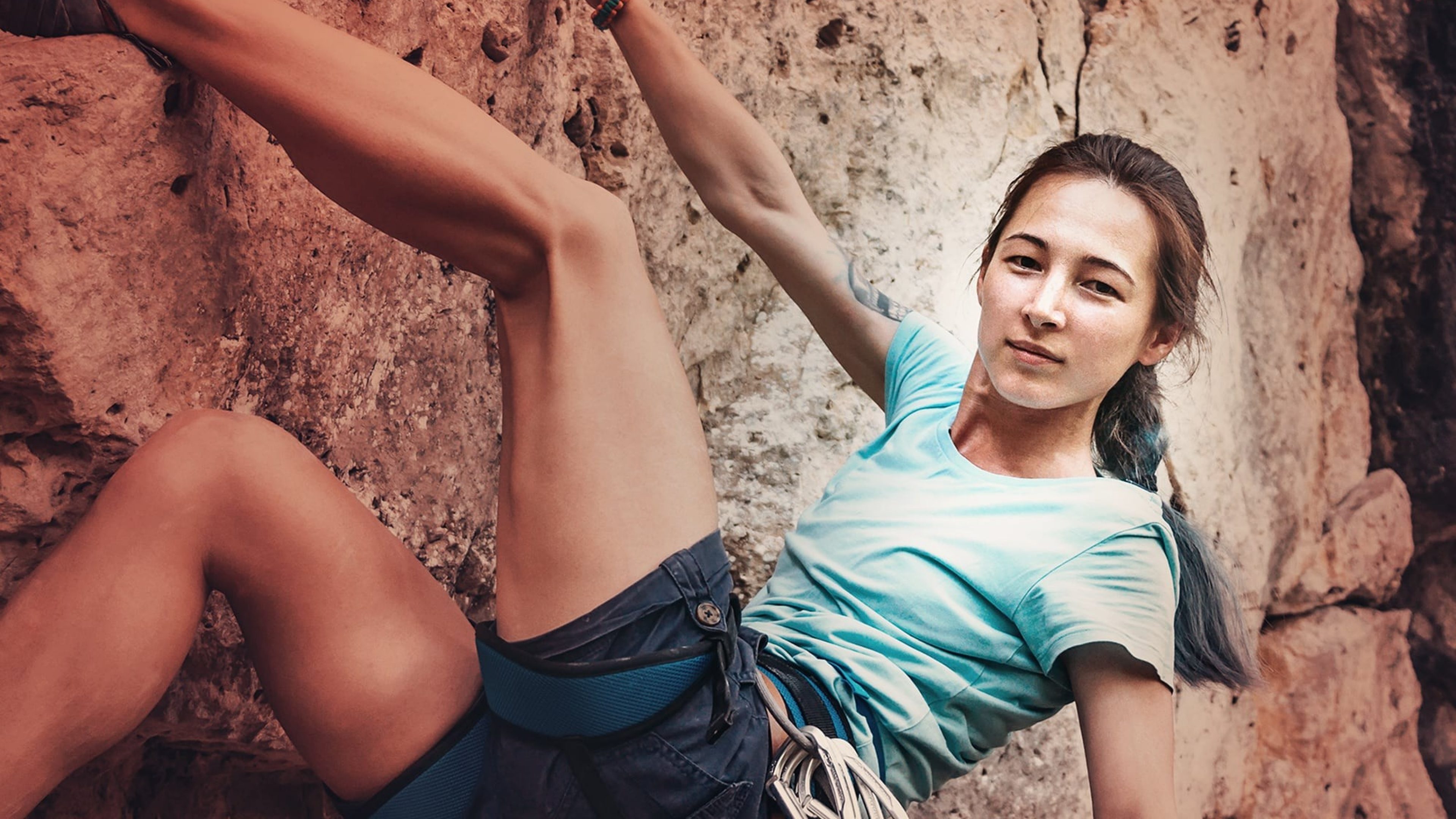 Frau klettert am Felsen hoch