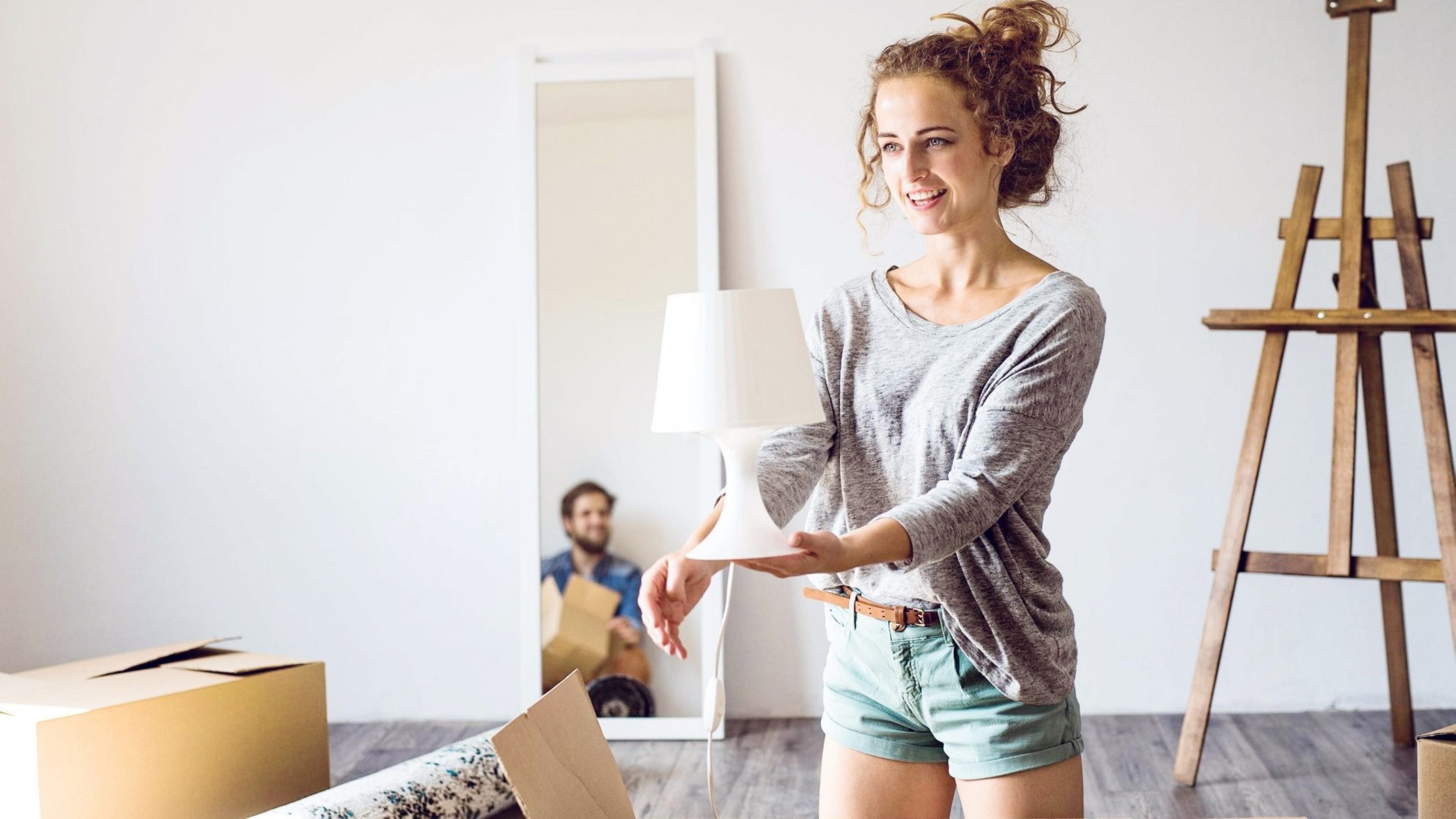 Frau in neuer Wohnung mit Lampe in der Hand