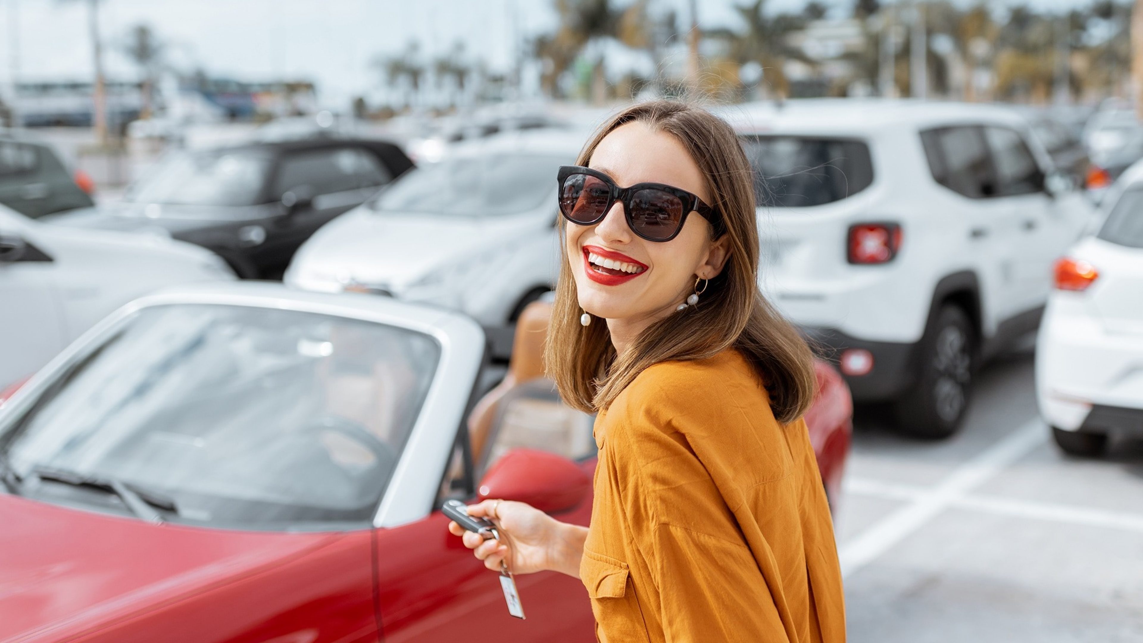 Frau mit Autoschlüssel vor rotem Cabrio