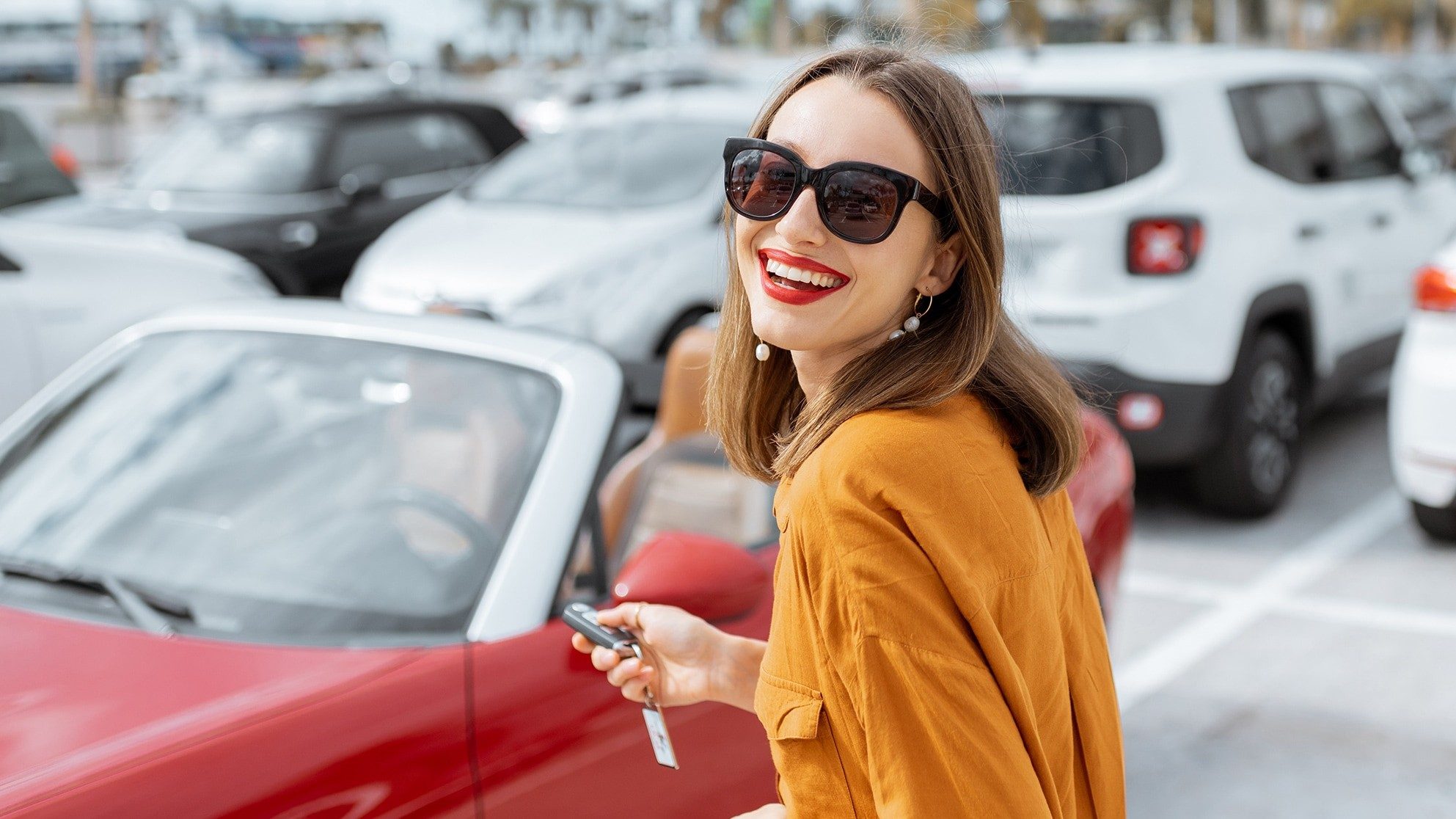 Lächelnde Frau auf Parkplatz mit Autoschlüssel