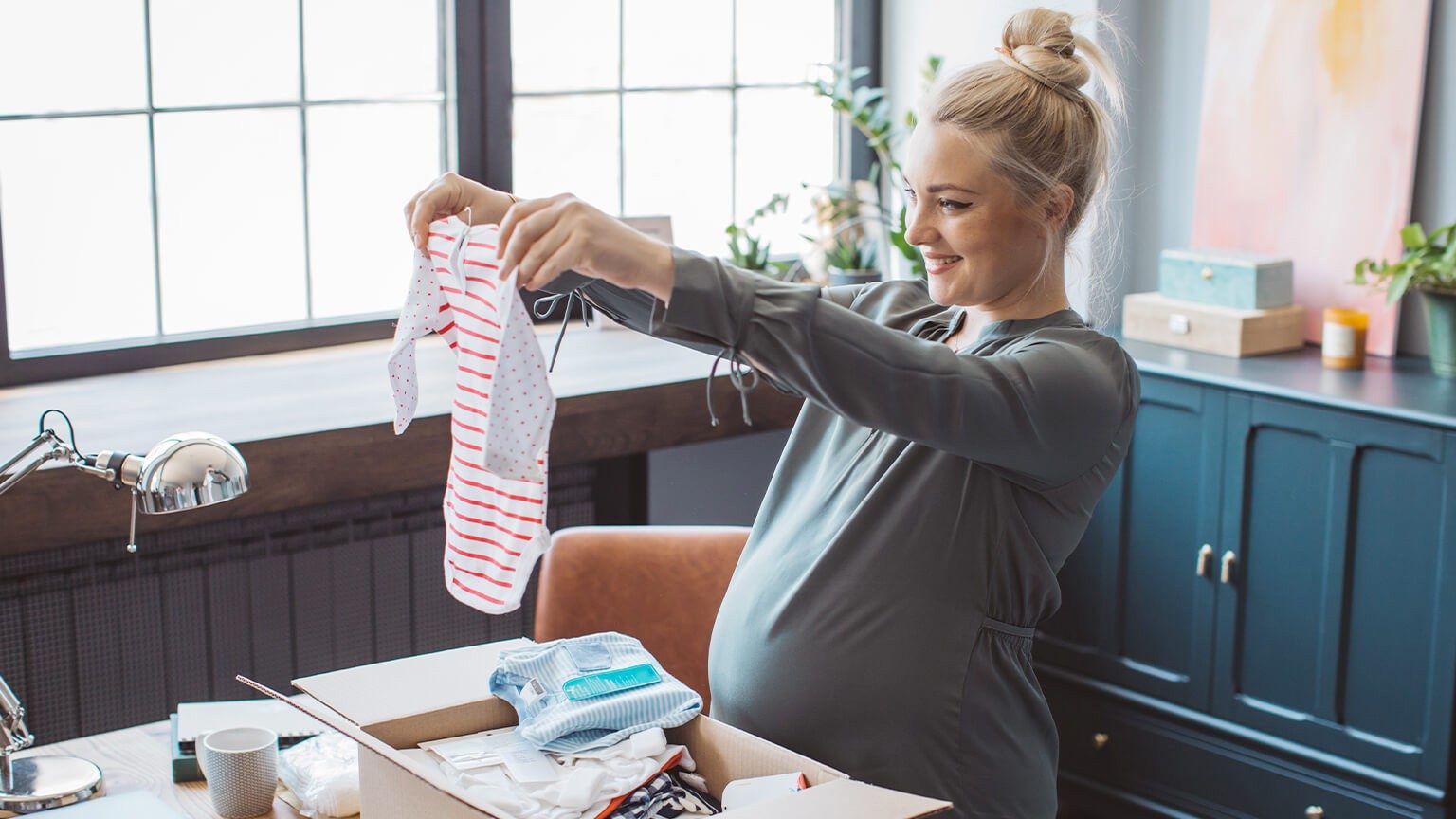 Schwangere Frau pack Babysachen aus