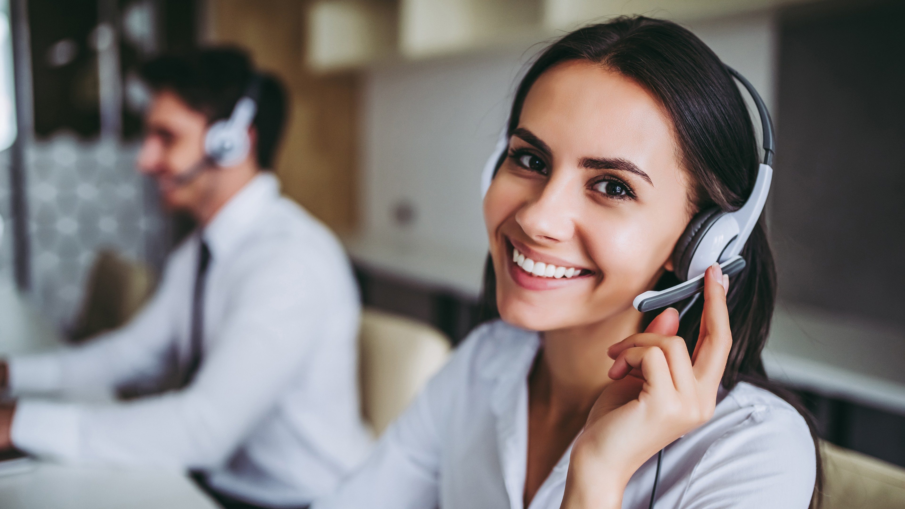 Mitarbeiterin Kundenservice mit Headset lächelt in die Kamera