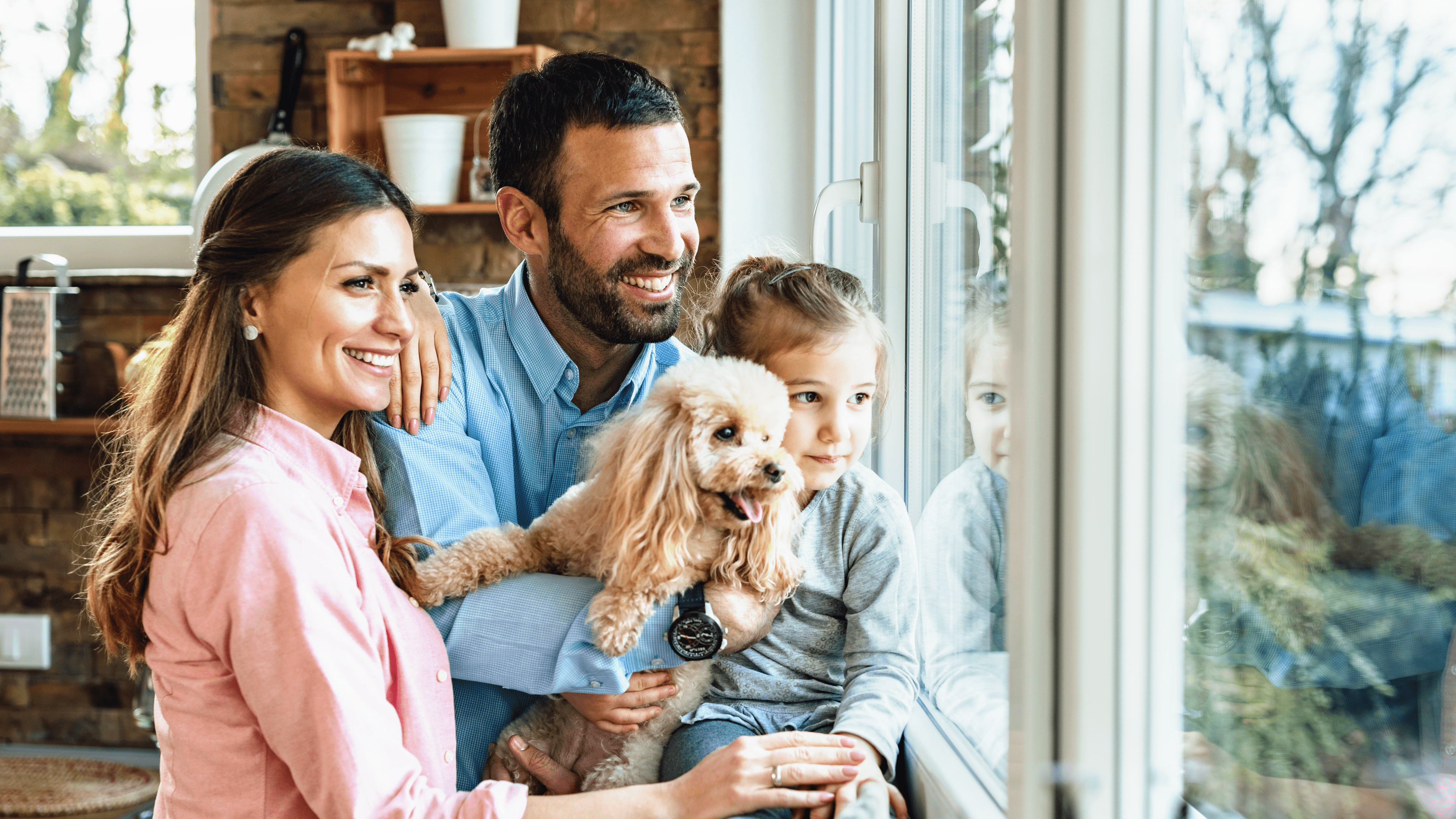 Familie mit Hund schaut aus dem Fenster