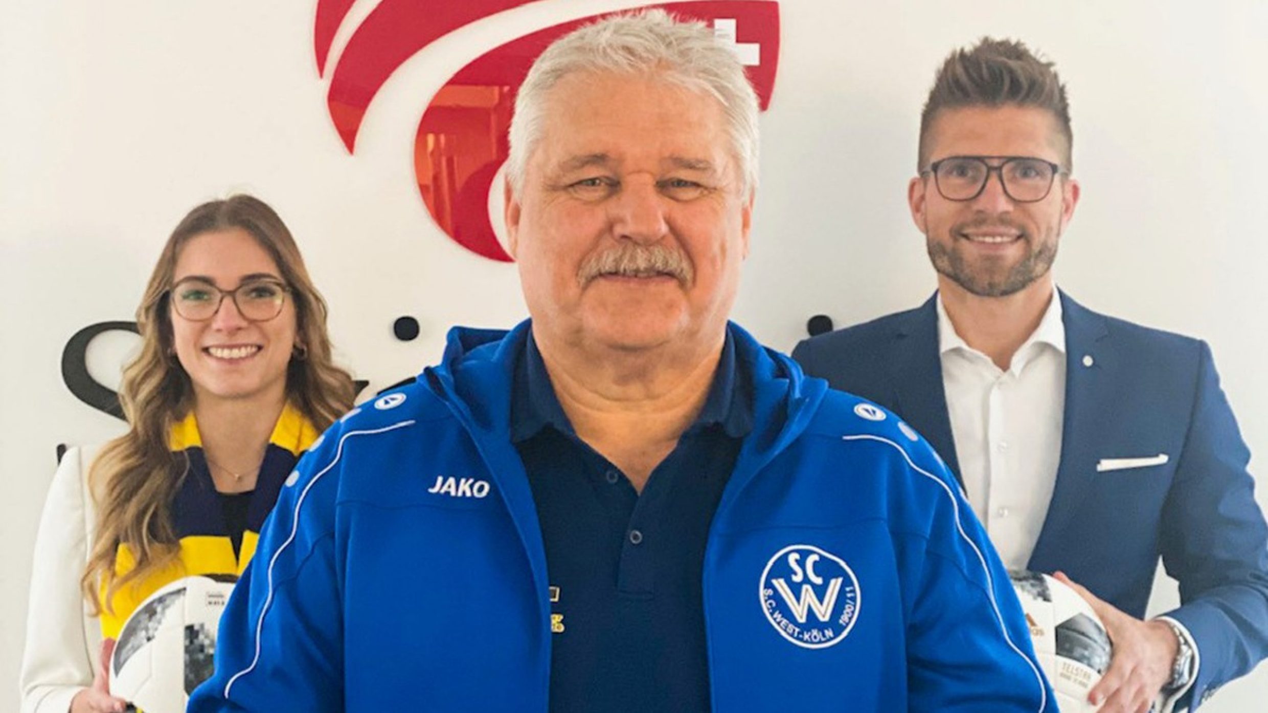 Direktor Thomas Olschewski und Vertriebspartnerin Theresa Hanke mit Fußballtrainer