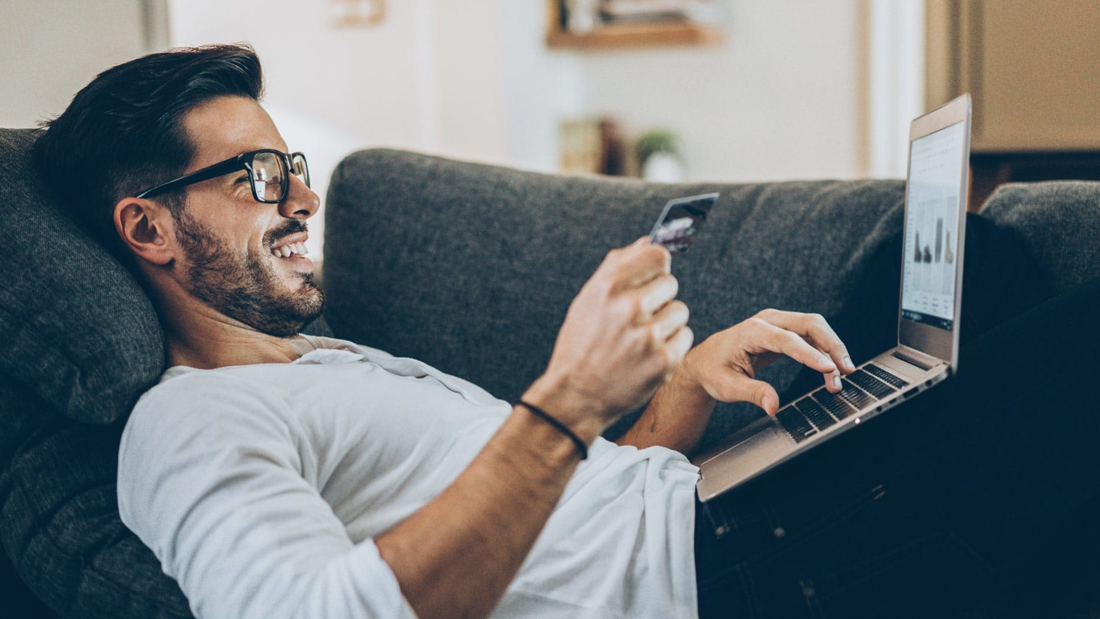 Mann mit Kreditkarte vor Laptop