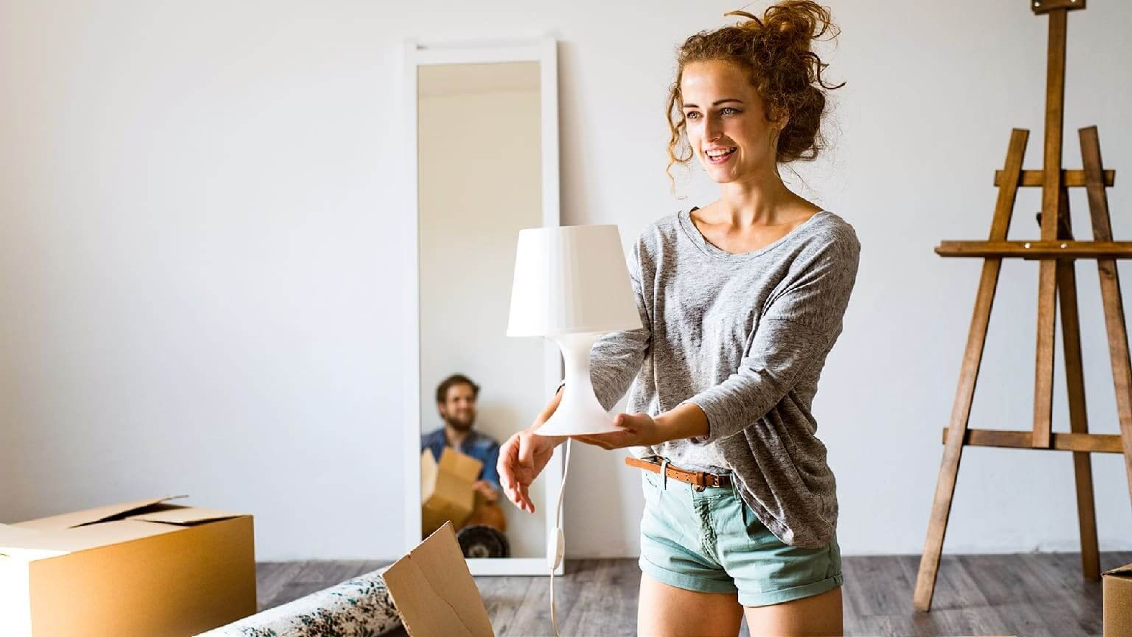 Frau in neuer Wohnung mit Lampe in der Hand